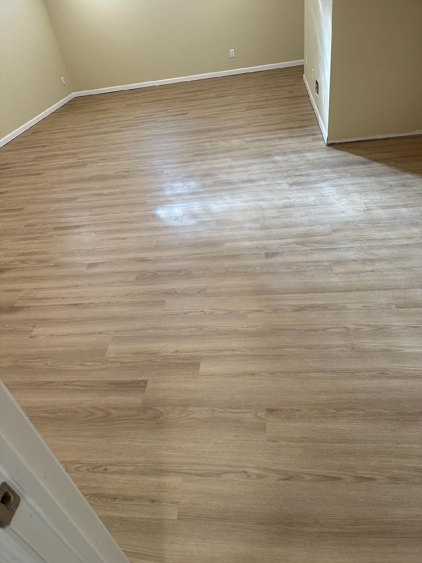 Empty beige room with wood-look flooring and an open doorway