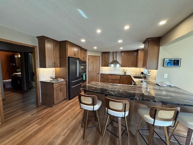 Modern kitchen with wood cabinets, stainless appliances, granite island, and three barstools