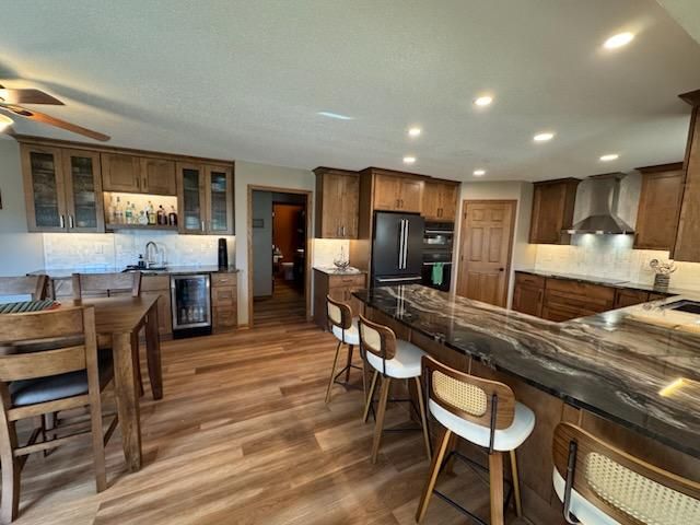 Open-plan kitchen with wood cabinets, granite island, bar stools, and dining table under recessed lights