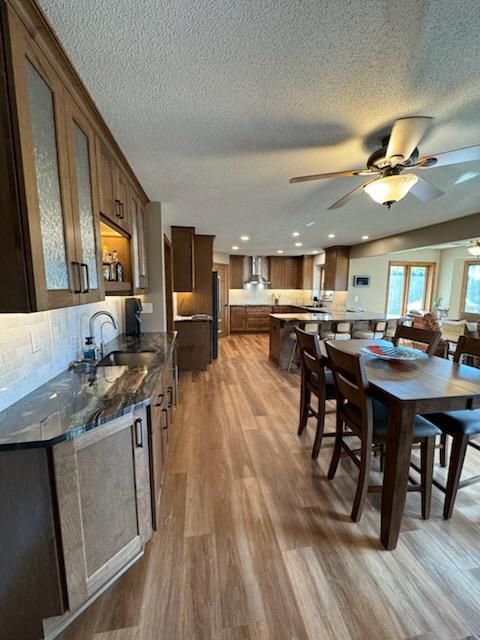 Open-concept kitchen and dining area with wood floors, island stools, and a ceiling fan.