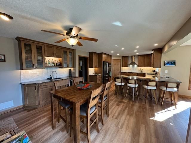 Modern open-concept kitchen and dining area with wood floors, island seating, and ceiling fan