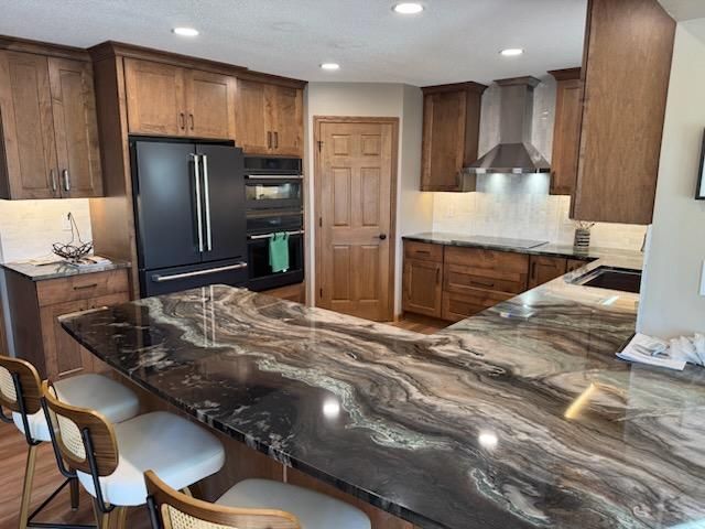 Modern kitchen with dark wood cabinets, stainless appliances, and a large marble island with barstools