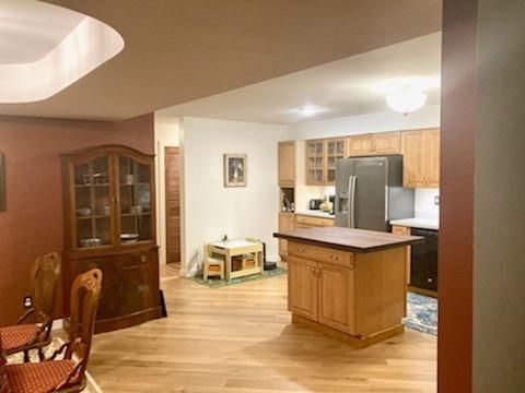 Open kitchen with wood cabinets, island, and dining area in a warmly lit home interior