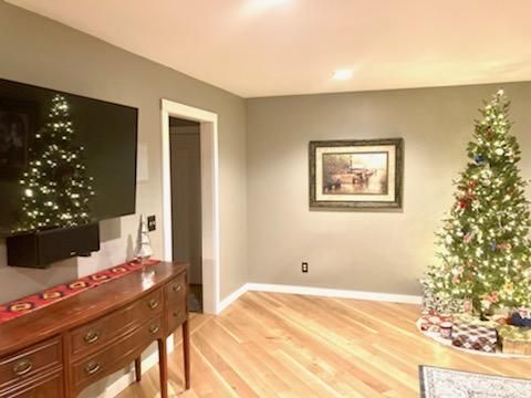 Living room with wall-mounted TV, wooden sideboard, framed art, and decorated Christmas tree