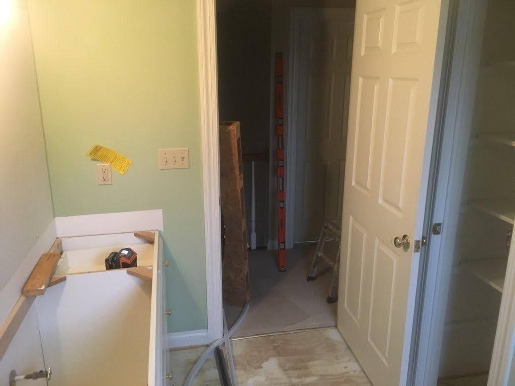 Small bathroom with a bathtub, pale green walls, and an open doorway to a hallway.