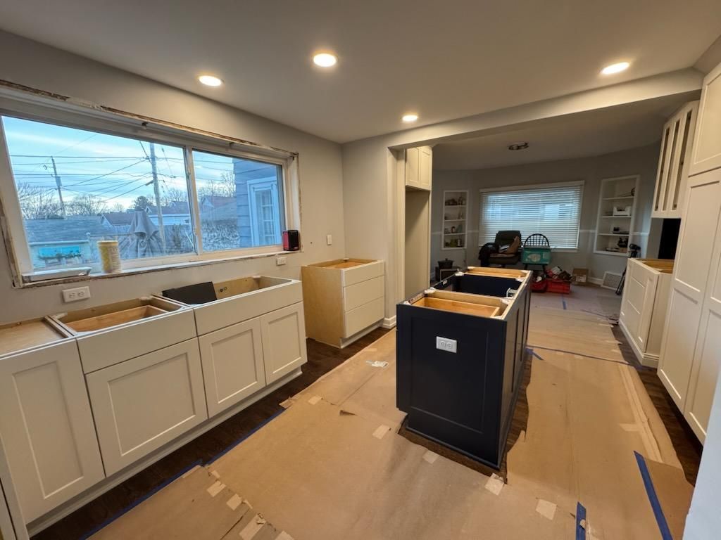 Kitchen under renovation with unfinished cabinets, island, and protective floor covering