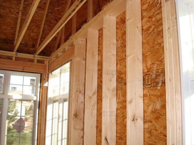 Framed interior wall with exposed studs and windows in an unfinished room