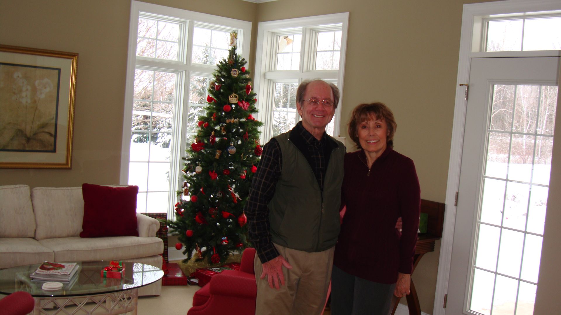 Couple standing by a decorated Christmas tree in a bright living room