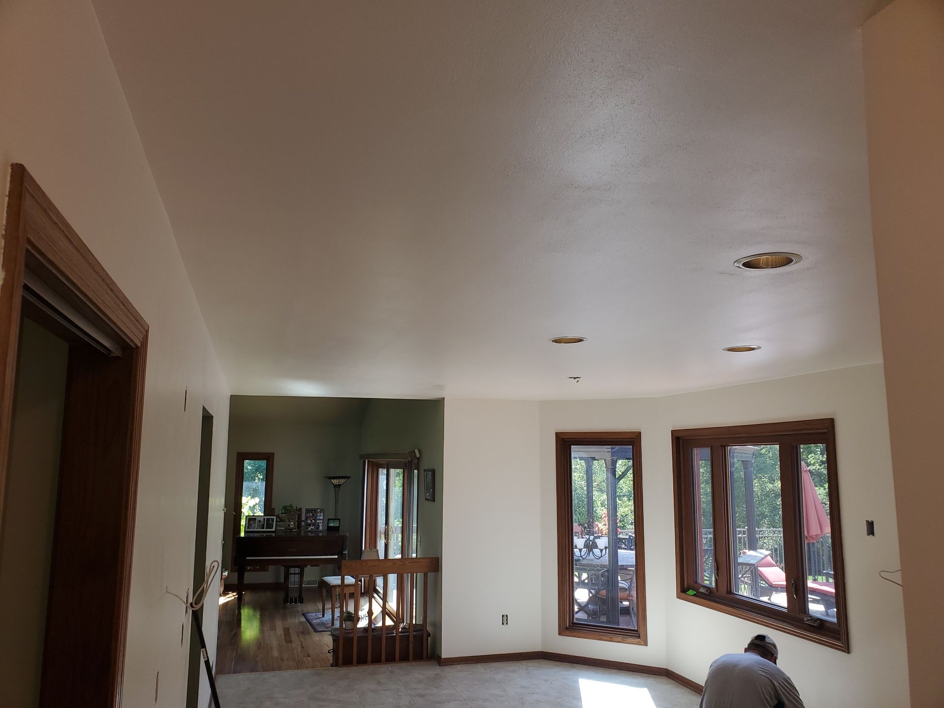 Empty living room with beige walls, white floor, and windows and glass doors letting in daylight