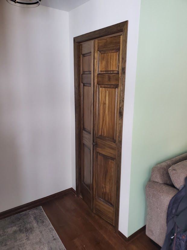 Wooden door in a hallway beside a beige couch and white walls