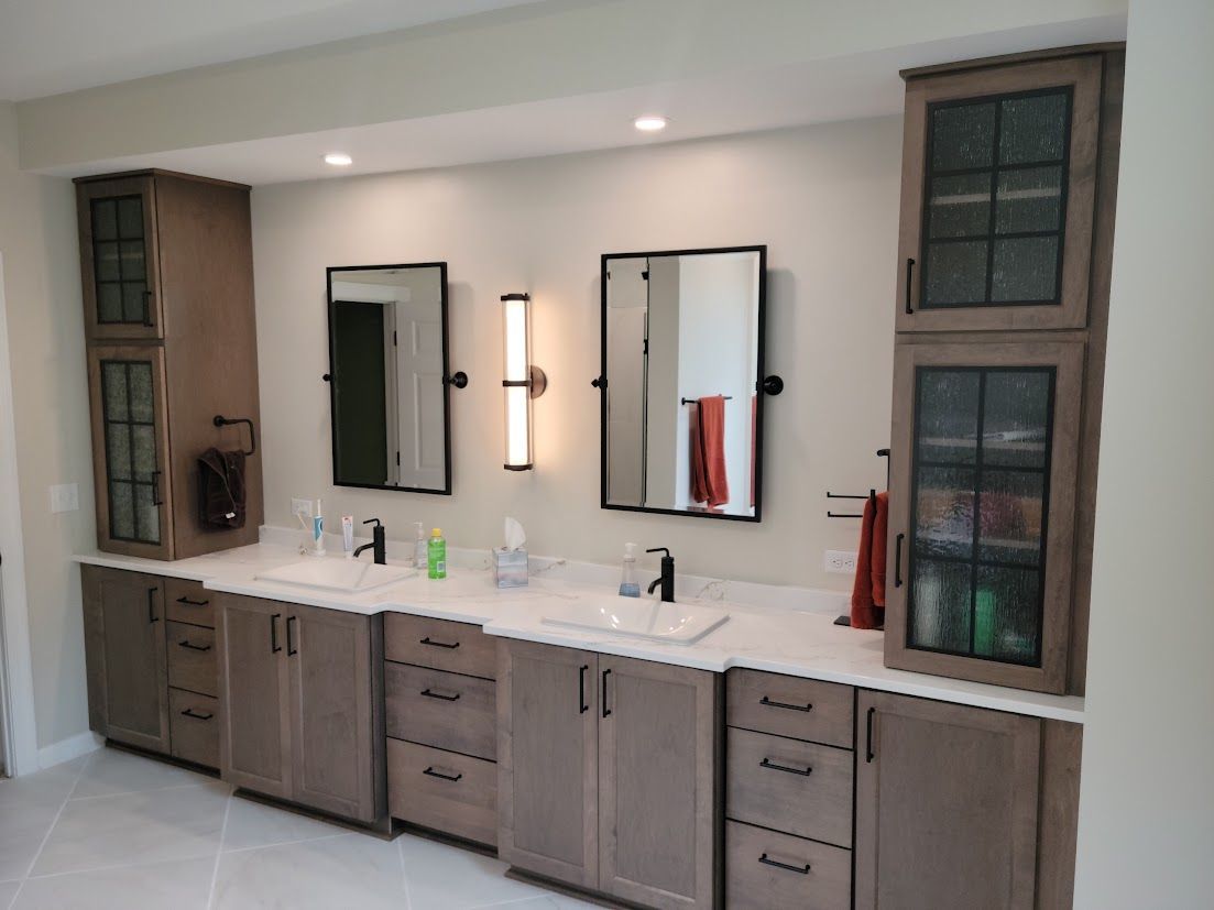 Modern bathroom vanity with three mirrors, gray cabinets, and a white countertop under recessed lights