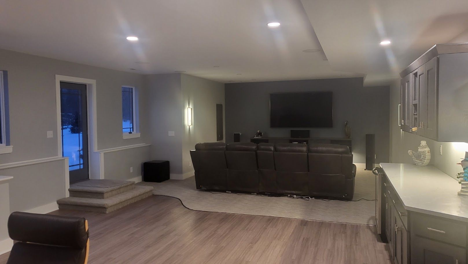 Modern open-concept living room with sectional sofa, TV, and kitchen island under warm lighting