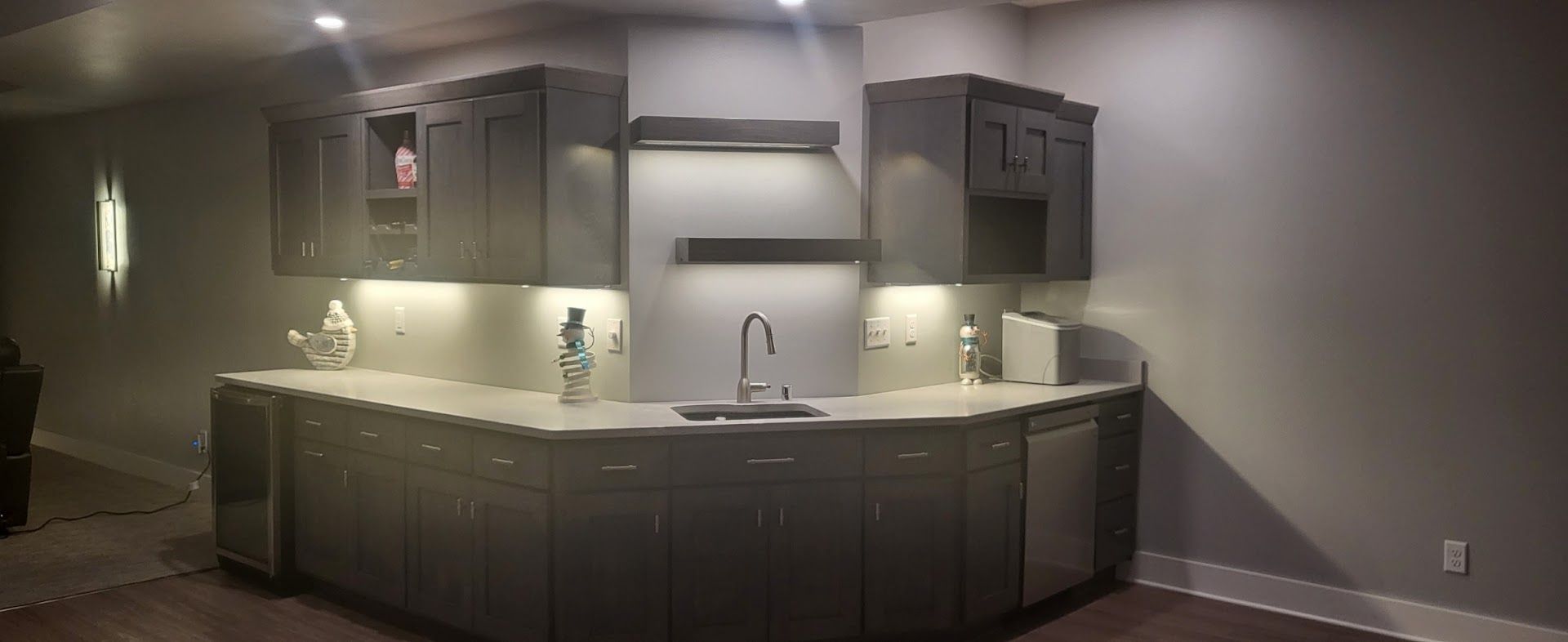Modern kitchen with dark cabinets, central sink, and under-cabinet lighting.