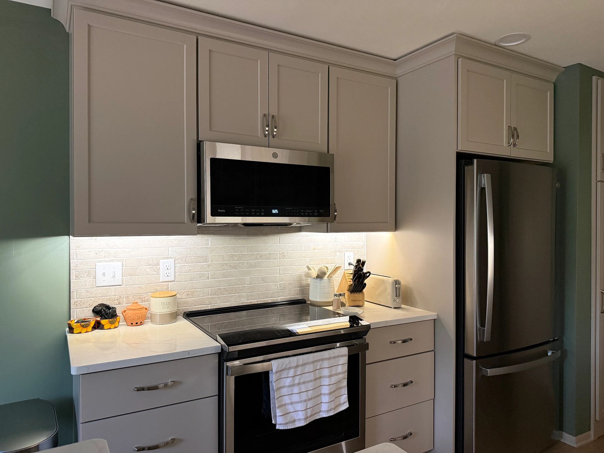 Modern kitchen countertop with sink, plants, and decorative baskets under warm under-cabinet lighting
