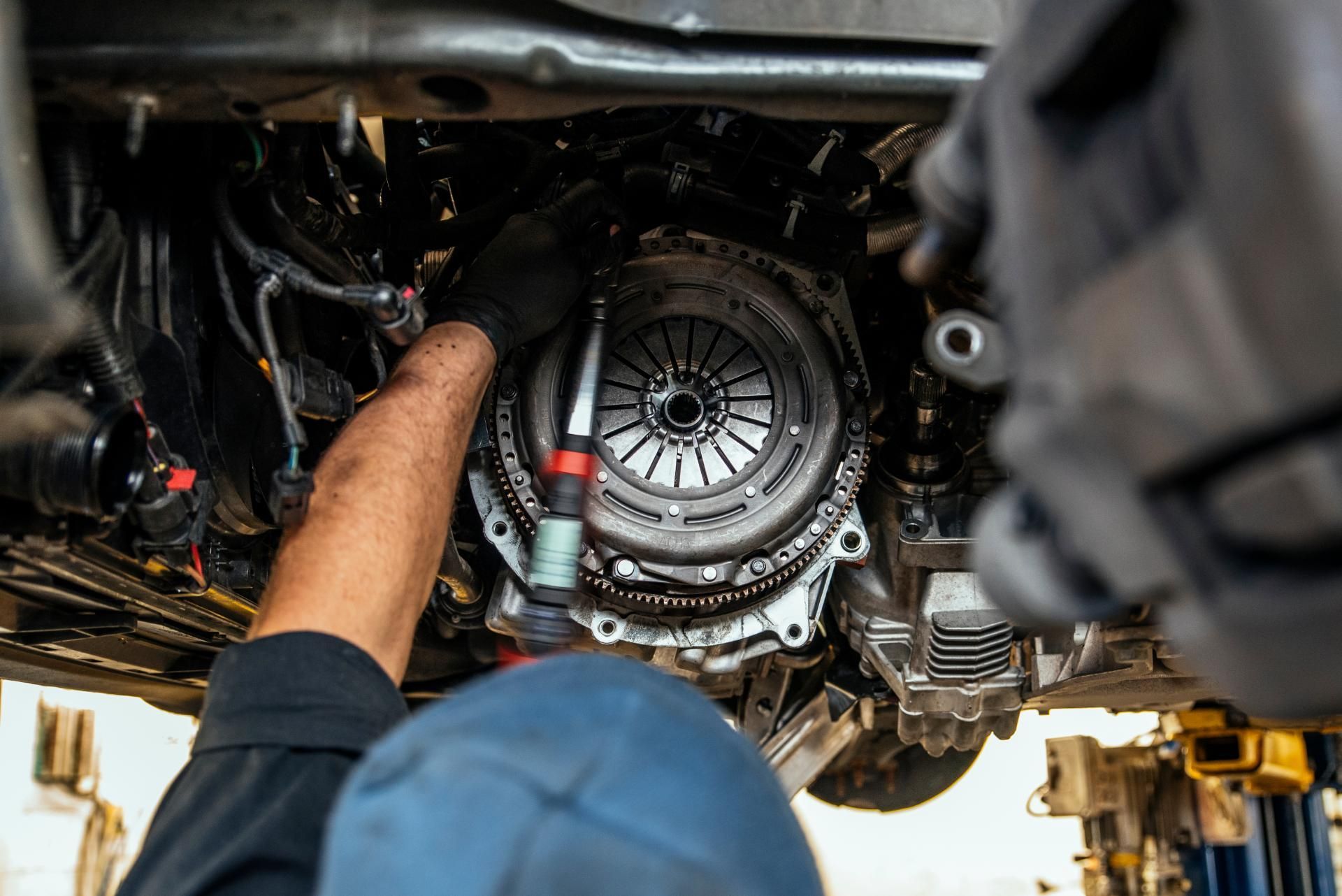 Mechanic working under a raised car, inspecting the transmission and drivetrain components
