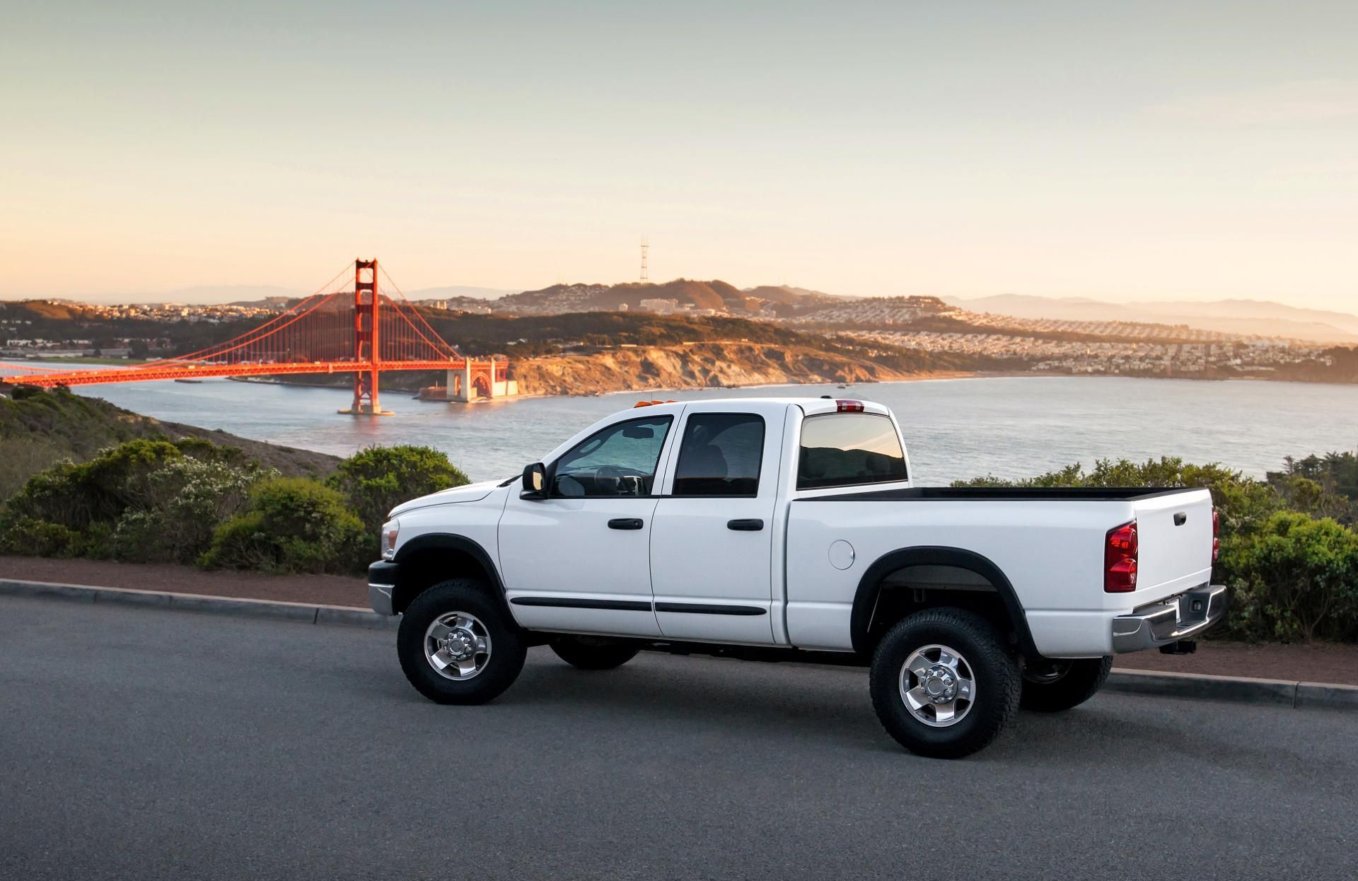 White pickup truck parked on a roadside overlooking the Golden Gate Bridge at sunset
