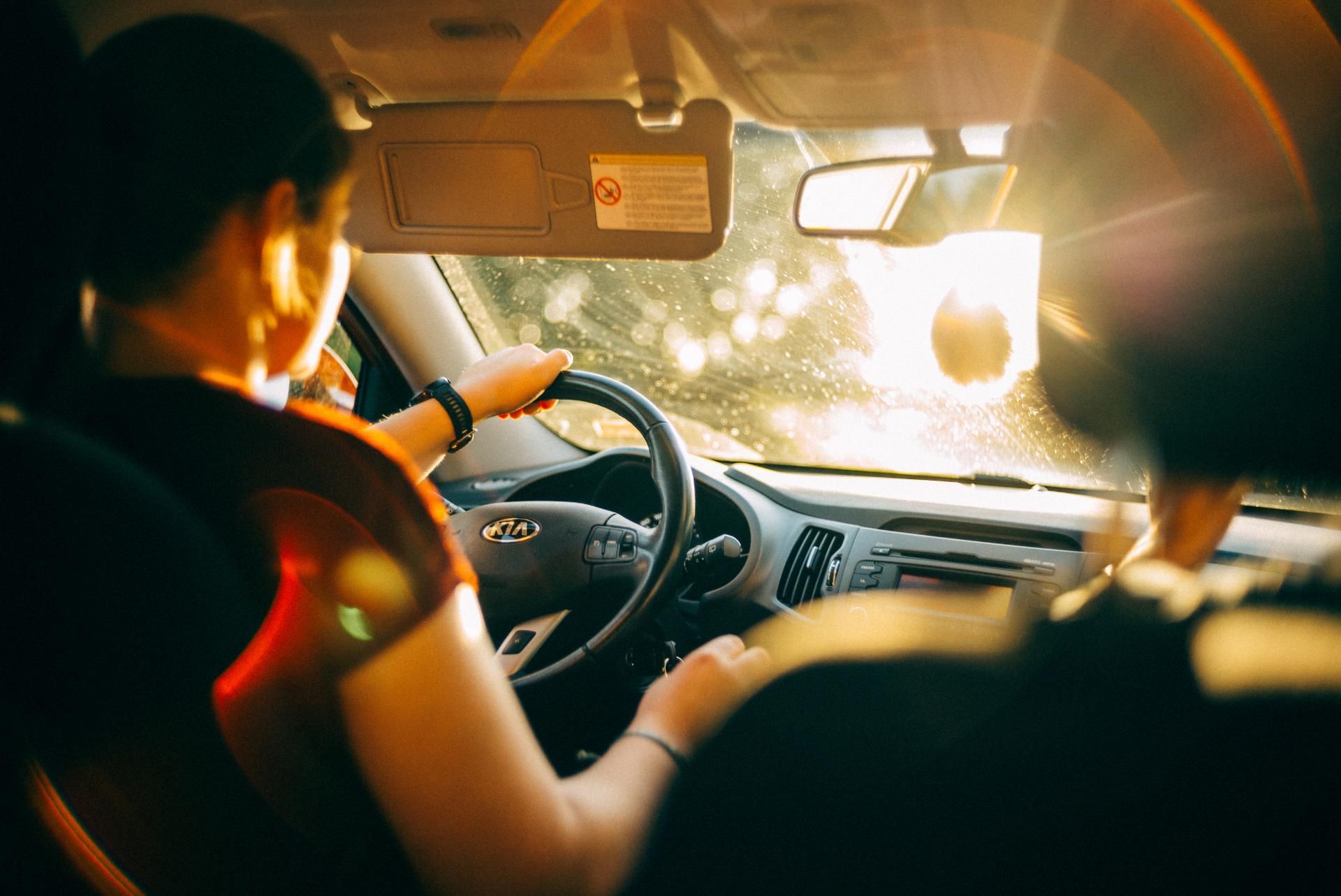 Driver and passenger in a car, sunlit windshield ahead during a drive