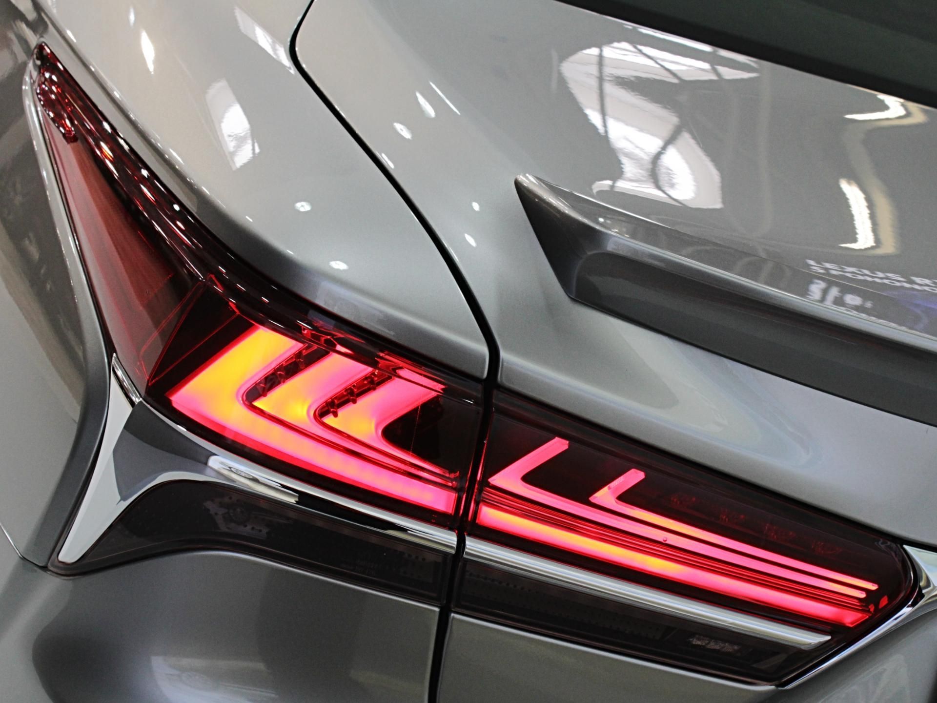 Close-up of a silver car’s rear taillight glowing red with a sharp angular design