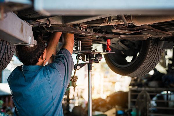 Mechanic working under a raised car in an auto repair shop