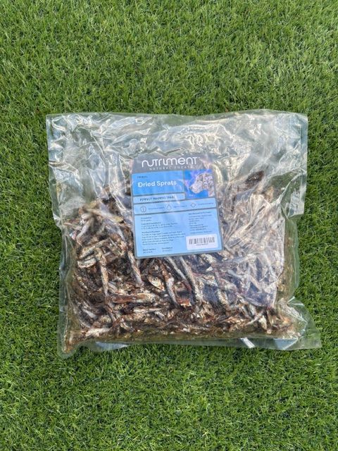 Clear plastic bag of dried food on green grass, with a blue label on the front.