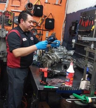 A man is working on a car engine in a garage.