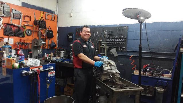 A man is standing in a garage working on a machine.