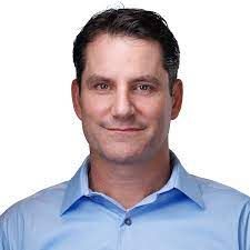 A man in a blue shirt is smiling for the camera.