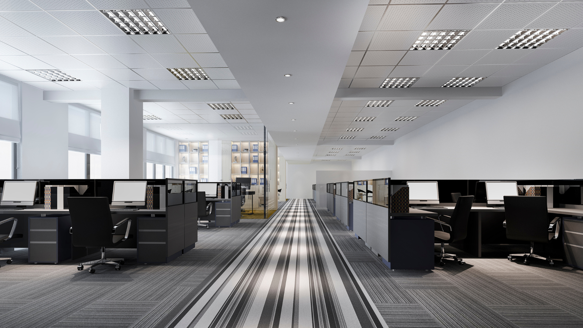 A long hallway in an office with cubicles and computers.
