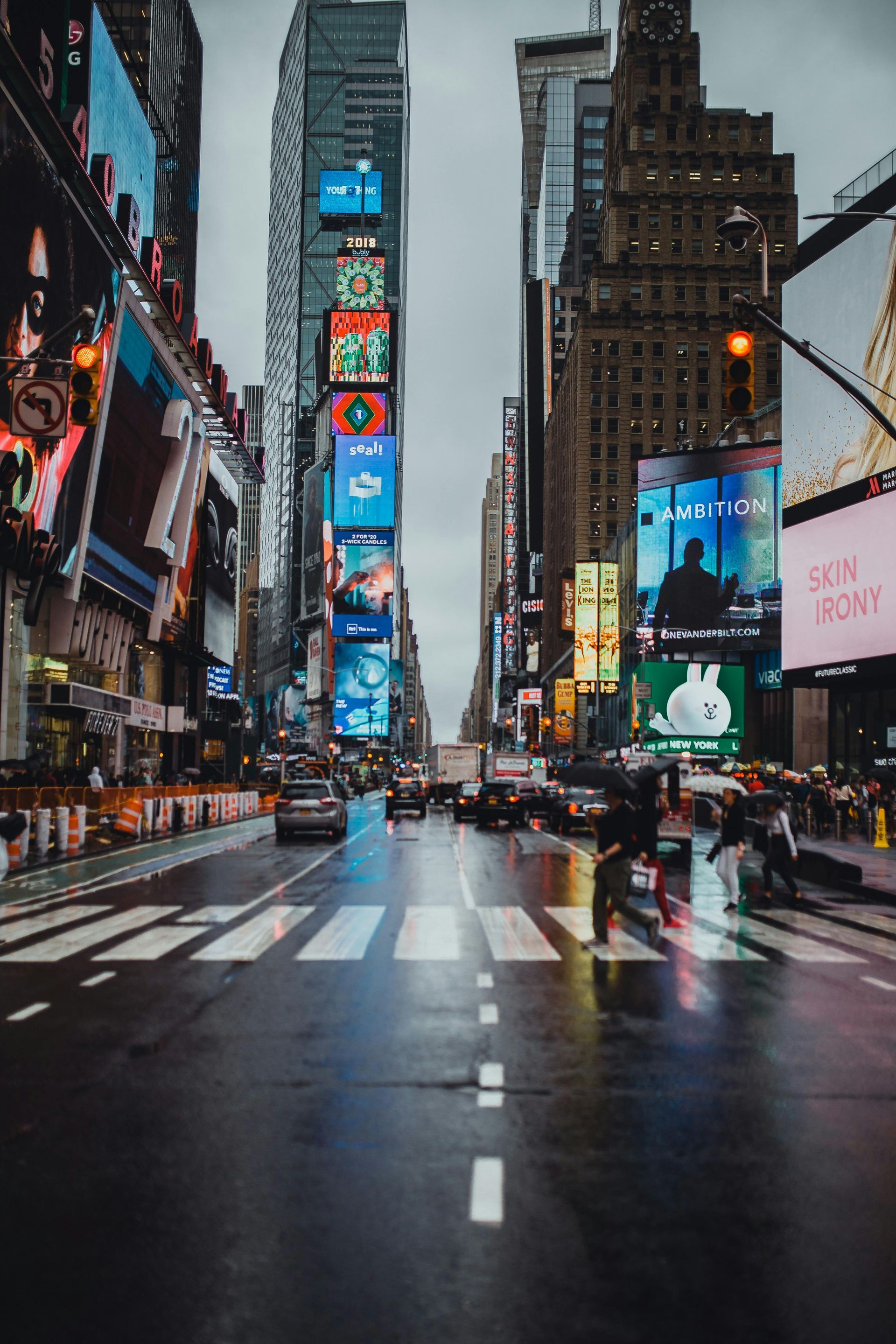 Rainy Times Square street with towering billboards and wet crosswalk in New York City