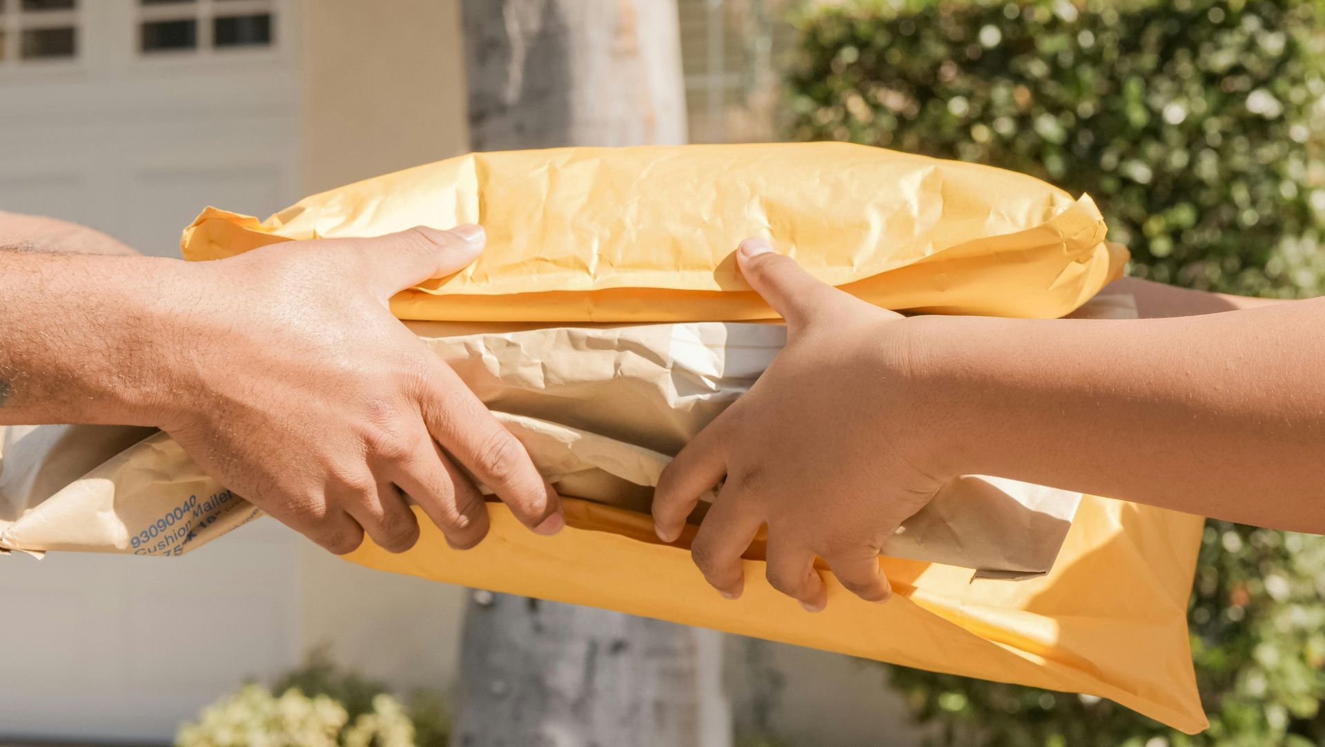 Hands passing a wrapped package outdoors in bright sunlight