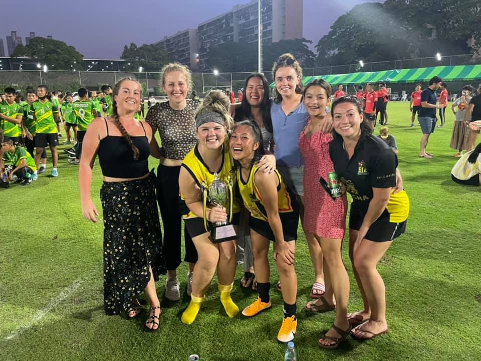 A group of women are posing for a picture on a soccer field.