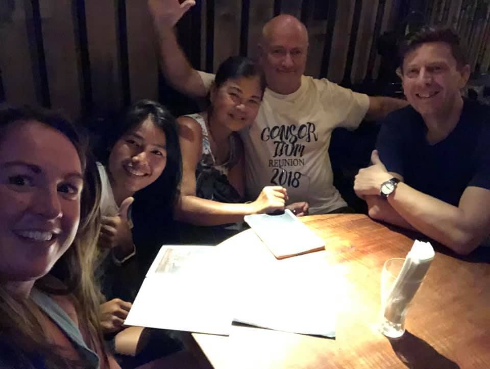A group of people are sitting around a table and one of them is wearing a t-shirt that says october 2007