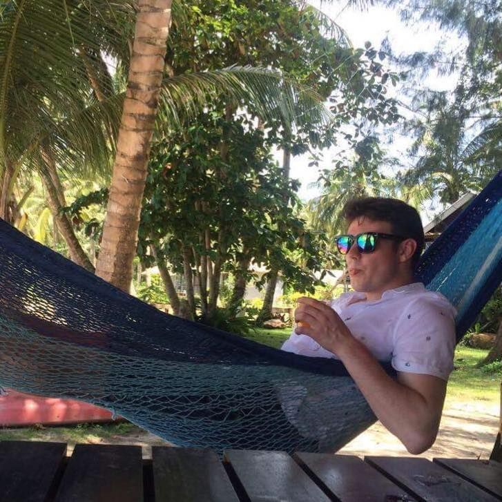 A man wearing sunglasses is laying in a hammock