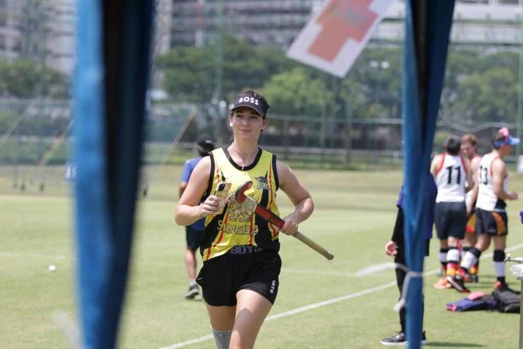 A woman is holding a lacrosse stick on a field.