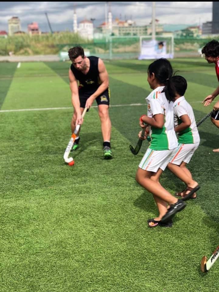A group of people are playing field hockey on a field.