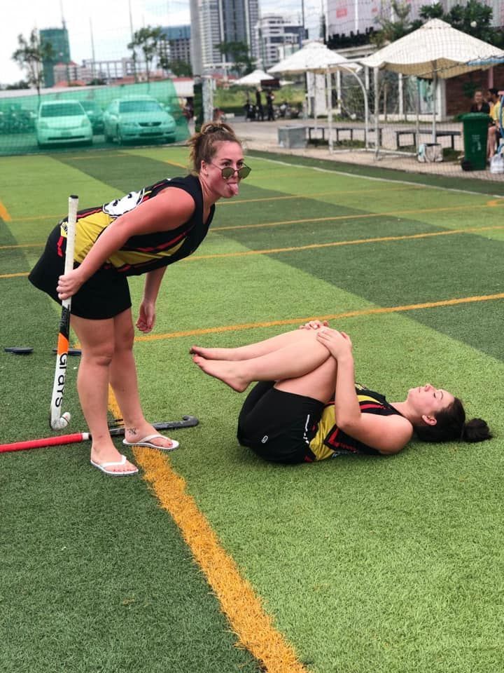 Two women are playing field hockey on a field.
