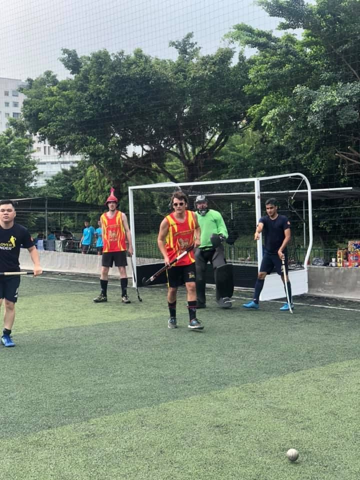 A group of men are playing field hockey on a field.