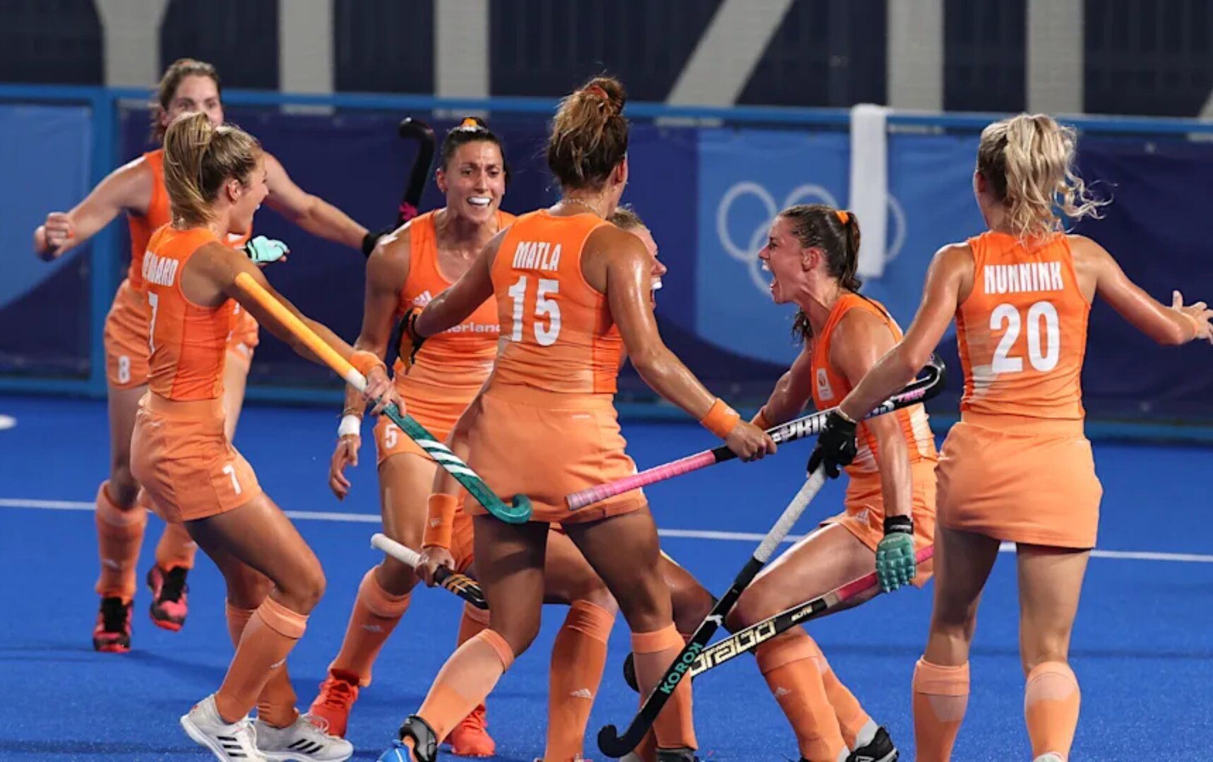 A group of women are playing field hockey on a field.