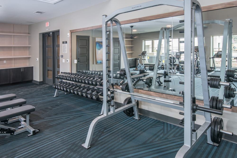 A gym with a lot of dumbbells and a lot of mirrors at Marquis Dominion in San Antonio, TX. 
