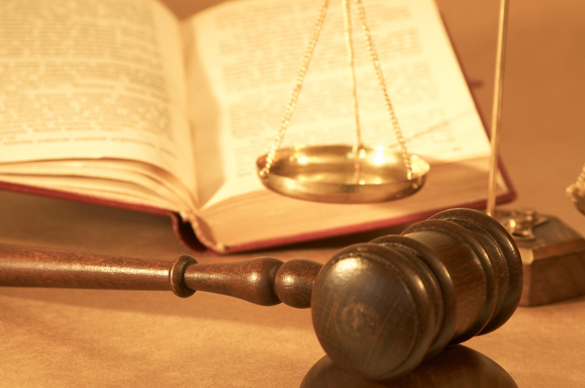 Wooden gavel, balanced scale, and open book, likely legal context.