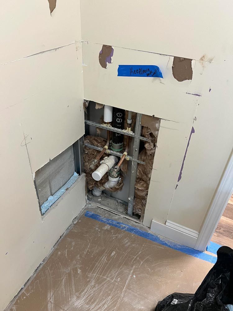 A bathroom with a hole in the wall and pipes coming out of it.