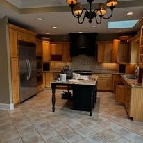 Modern kitchen with wood cabinets, stainless fridge, granite island, and tiled floor