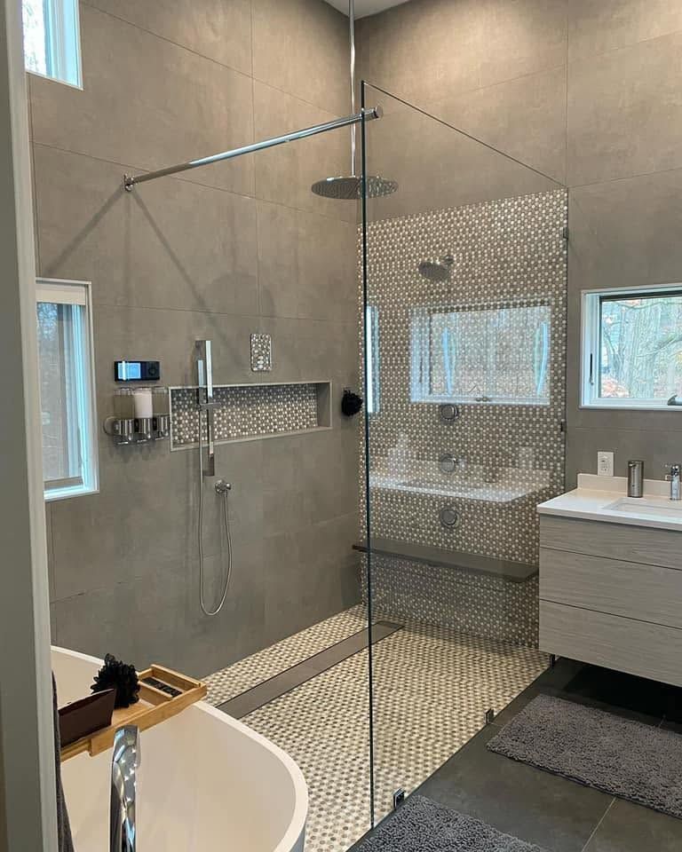 Modern bathroom with glass walk-in shower, gray tile walls, and a white vanity.