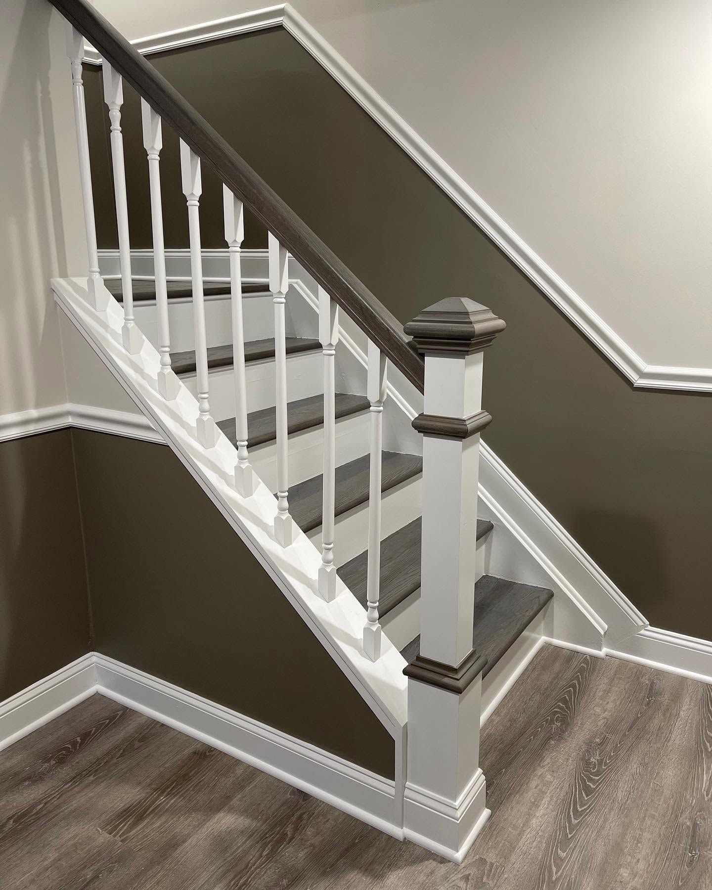 Interior staircase with white balusters, dark gray walls, and wood flooring in a hallway