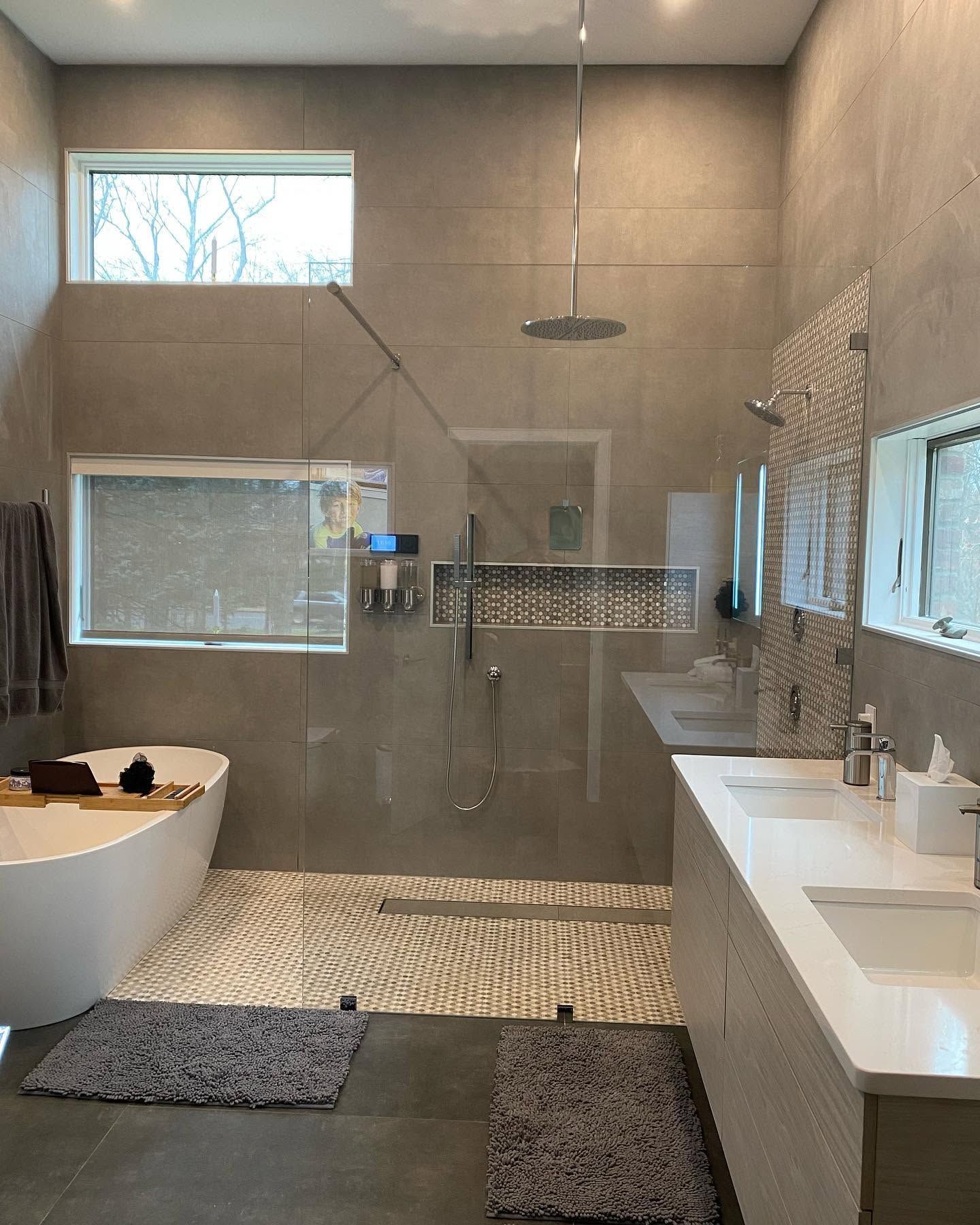 Modern bathroom with glass shower, bathtub, double sink vanity, and pebble tile accents