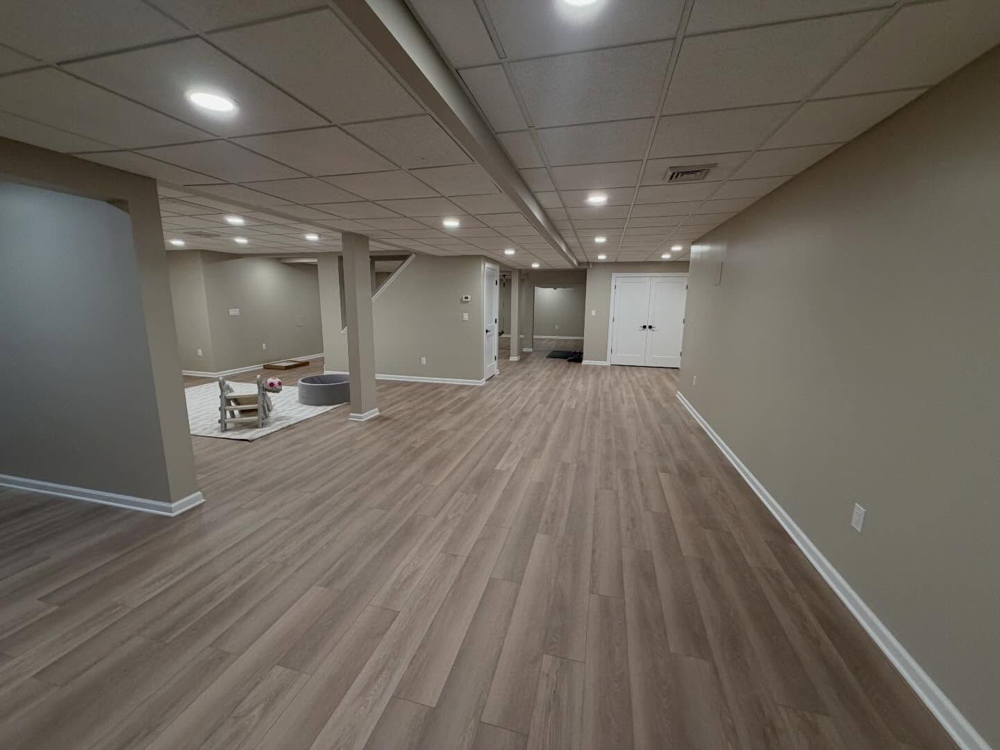Empty basement room with gray walls, wood-look floor, and recessed ceiling lights