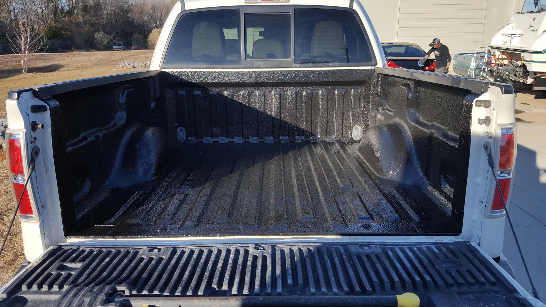 A white truck with a black bed is parked in a parking lot.