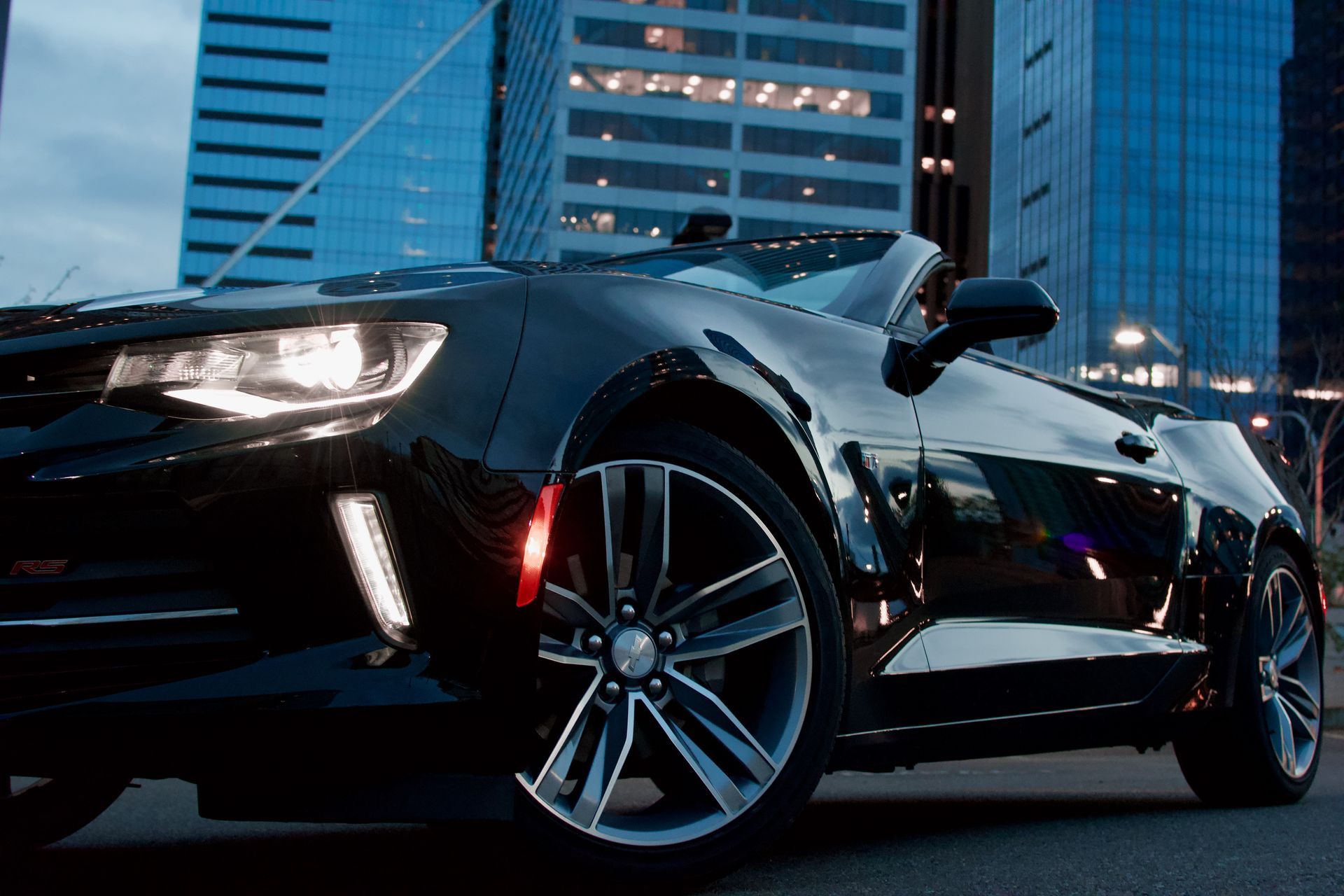 A black convertible car is parked in front of a city skyline.