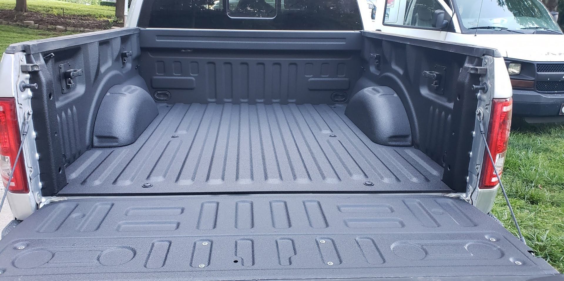 The back of a pickup truck with the bed painted black.
