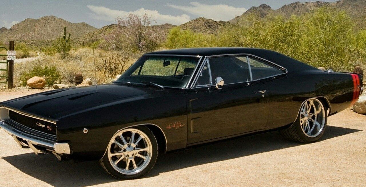 A black dodge charger is parked in the desert